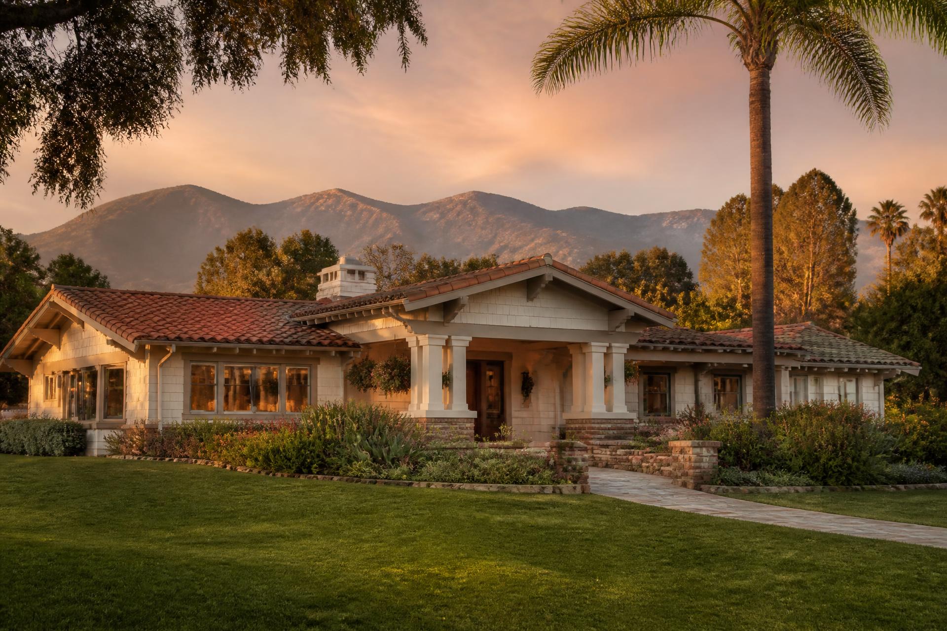 Two-story stucco Ventura County family home with tile roof and green lawn lit by warm golden-hour sun
